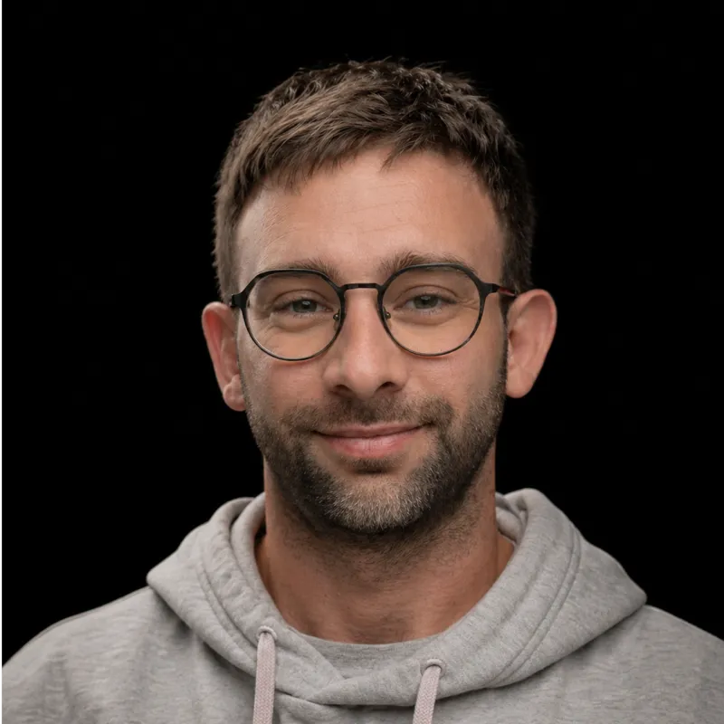 Erik Pastor — glasses, grey hoodie, against a black studio backdrop